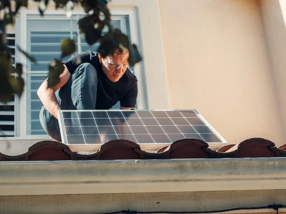 man installing solar panel of roof of home